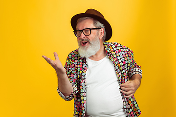 Image showing Senior hipster man wearing eyeglasses posing on yellow background. Tech and joyful elderly lifestyle concept