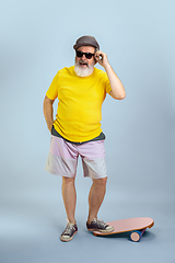 Image showing Senior hipster man wearing eyeglasses posing on light blue background. Tech and joyful elderly lifestyle concept