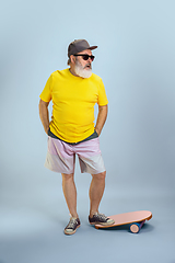 Image showing Senior hipster man wearing eyeglasses posing on light blue background. Tech and joyful elderly lifestyle concept