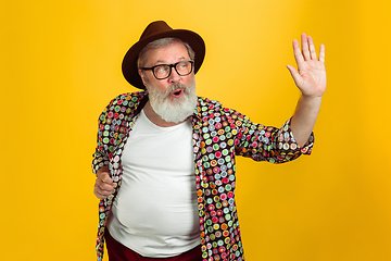 Image showing Senior hipster man wearing eyeglasses posing on yellow background. Tech and joyful elderly lifestyle concept