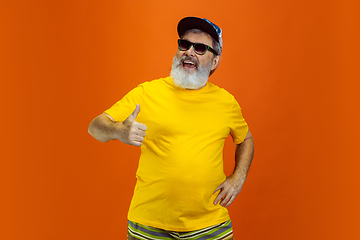 Image showing Senior hipster man wearing eyeglasses posing on orange background. Tech and joyful elderly lifestyle concept