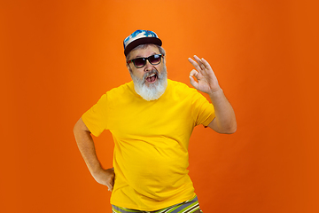 Image showing Senior hipster man wearing eyeglasses posing on orange background. Tech and joyful elderly lifestyle concept