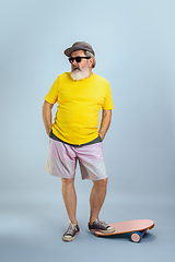 Image showing Senior hipster man wearing eyeglasses posing on light blue background. Tech and joyful elderly lifestyle concept