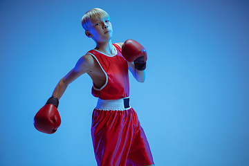 Image showing Teenager in sportswear boxing isolated on blue studio background in neon light