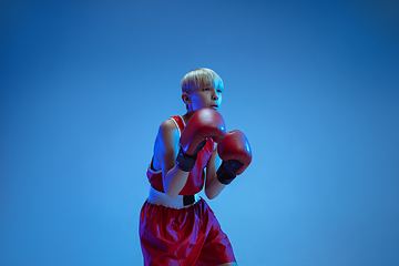 Image showing Teenager in sportswear boxing isolated on blue studio background in neon light