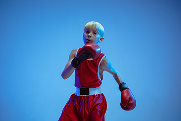 Image showing Teenager in sportswear boxing isolated on blue studio background in neon light