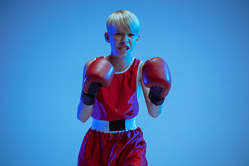Image showing Teenager in sportswear boxing isolated on blue studio background in neon light