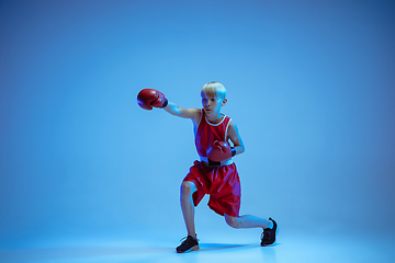 Image showing Teenager in sportswear boxing isolated on blue studio background in neon light