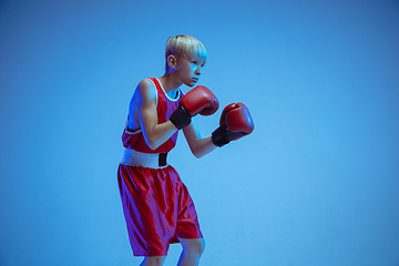 Image showing Teenager in sportswear boxing isolated on blue studio background in neon light