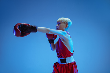 Image showing Teenager in sportswear boxing isolated on blue studio background in neon light