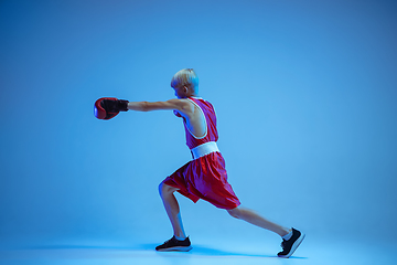 Image showing Teenager in sportswear boxing isolated on blue studio background in neon light