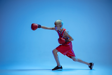 Image showing Teenager in sportswear boxing isolated on blue studio background in neon light