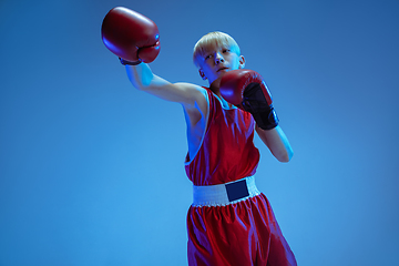 Image showing Teenager in sportswear boxing isolated on blue studio background in neon light