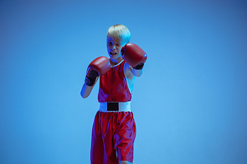 Image showing Teenager in sportswear boxing isolated on blue studio background in neon light