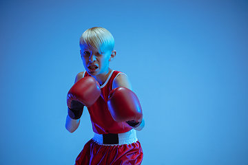 Image showing Teenager in sportswear boxing isolated on blue studio background in neon light