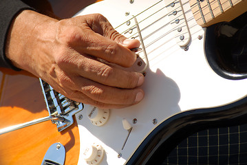Image showing A closeup of a man playing a guitar