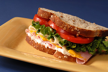 Image showing Ham, cheese, lettuce and tomato sandwich on yellow plate