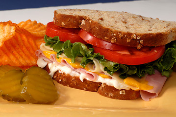 Image showing Ham, cheese, lettuce and tomato sandwich with pickles and chips