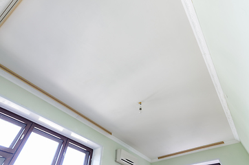 Image showing Plastered white ceiling in the room, a temporary light bulb hangs on the ceiling