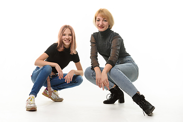 Image showing Mother and teenage daughter sat on their knees and cheerfully look into the frame