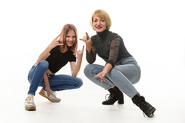 Image showing Mother and daughter teenager knelt down and cheerfully show youth gestures in the frame