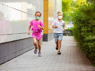 Image showing Happy little caucasian kids jumping and running on the city street