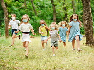 Image showing Happy little caucasian kids jumping and running on the meadow, in forest