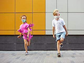 Image showing Happy little caucasian kids jumping and running on the city street