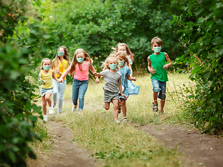 Image showing Happy little caucasian kids jumping and running on the meadow, in forest