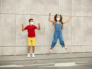 Image showing Happy little caucasian kids jumping and running on the city street