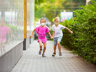 Image showing Happy little caucasian kids jumping and running on the city street