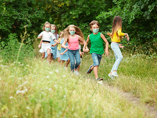 Image showing Happy little caucasian kids jumping and running on the meadow, in forest