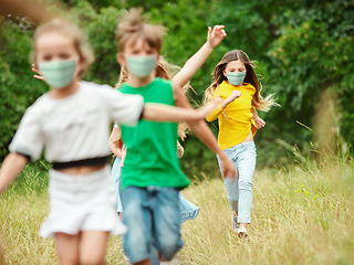 Image showing Happy little caucasian kids jumping and running on the meadow, in forest