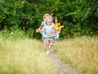 Image showing Happy little caucasian kids jumping and running on the meadow, in forest