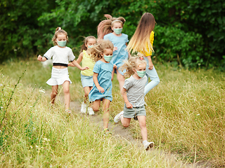 Image showing Happy little caucasian kids jumping and running on the meadow, in forest