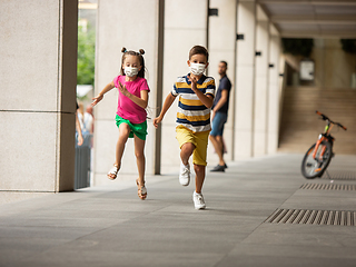 Image showing Happy little caucasian kids jumping and running on the city street