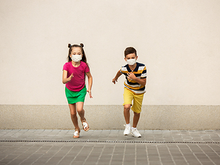 Image showing Happy little caucasian kids jumping and running on the city street