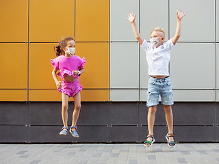Image showing Happy little caucasian kids jumping and running on the city street