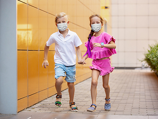 Image showing Happy little caucasian kids jumping and running on the city street