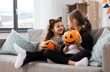 Image showing girls in halloween costumes with pumpkins at home