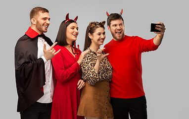 Image showing happy friends in halloween costumes taking selfie