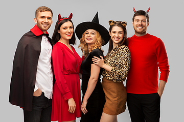 Image showing happy friends in halloween costumes over grey