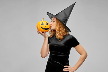 Image showing woman in halloween costume of witch kisses pumpkin