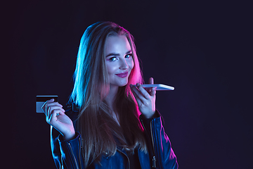 Image showing Portrait of young woman in neon light on dark backgound. The human emotions, black friday, cyber monday, purchases, sales, finance concept.