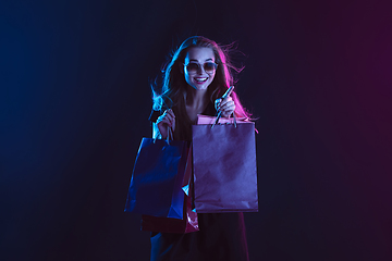 Image showing Portrait of young woman in neon light on dark backgound. The human emotions, black friday, cyber monday, purchases, sales, finance concept.