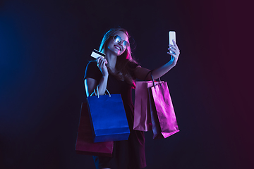 Image showing Portrait of young woman in neon light on dark backgound. The human emotions, black friday, cyber monday, purchases, sales, finance concept.