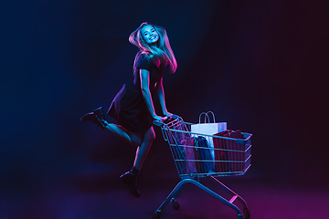 Image showing Portrait of young woman in neon light on dark backgound. The human emotions, black friday, cyber monday, purchases, sales, finance concept.