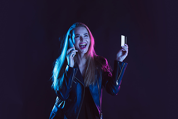 Image showing Portrait of young woman in neon light on dark backgound. The human emotions, black friday, cyber monday, purchases, sales, finance concept.