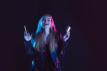 Image showing Portrait of young woman in neon light on dark backgound. The human emotions, black friday, cyber monday, purchases, sales, finance concept.