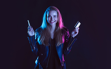 Image showing Portrait of young woman in neon light on dark backgound. The human emotions, black friday, cyber monday, purchases, sales, finance concept.